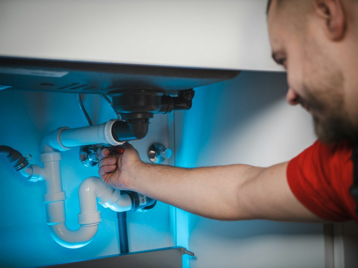 Licensed Pine Rooter plumber repairing pipes under a sink in Bothell, WA