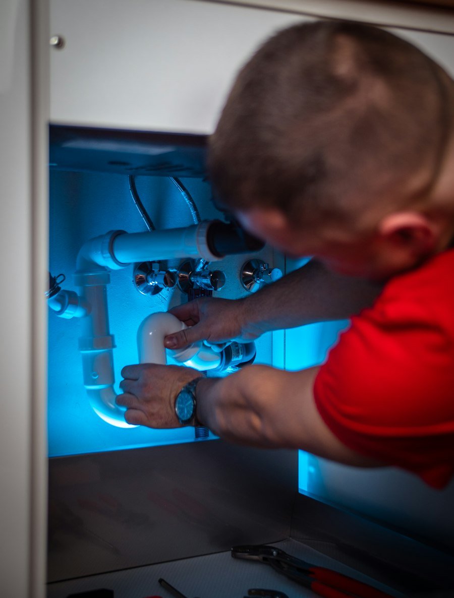 Pine Rooter technician diagnosing a pipe repair under a kitchen sink
